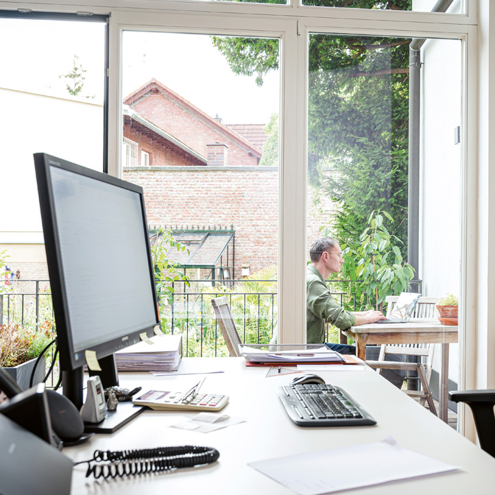 Blick aus Büro auf den Balkon und Wolfgang Wiese vor einem Notebook